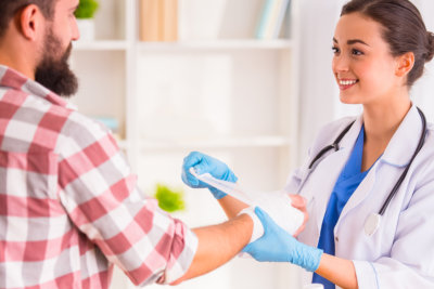 photo of a woman putting bandage on a man hands