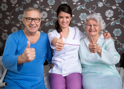 two elderly people with caregiver smiling